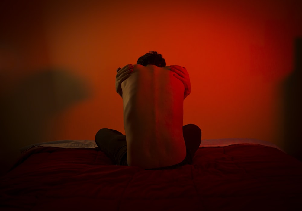 man in black shirt sitting on bed