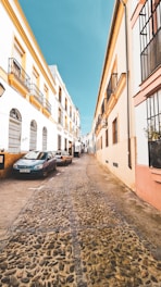 blue car parked beside beige concrete building during daytime