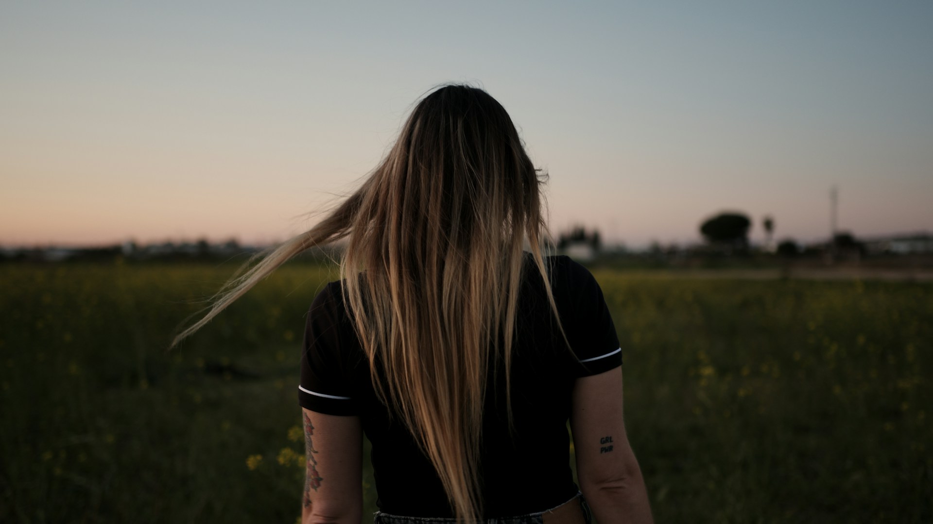 woman in black t-shirt standing on green grass field during daytime