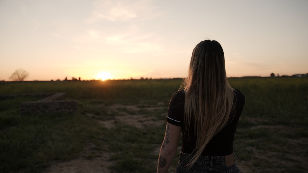 woman in black jacket standing on field during sunset