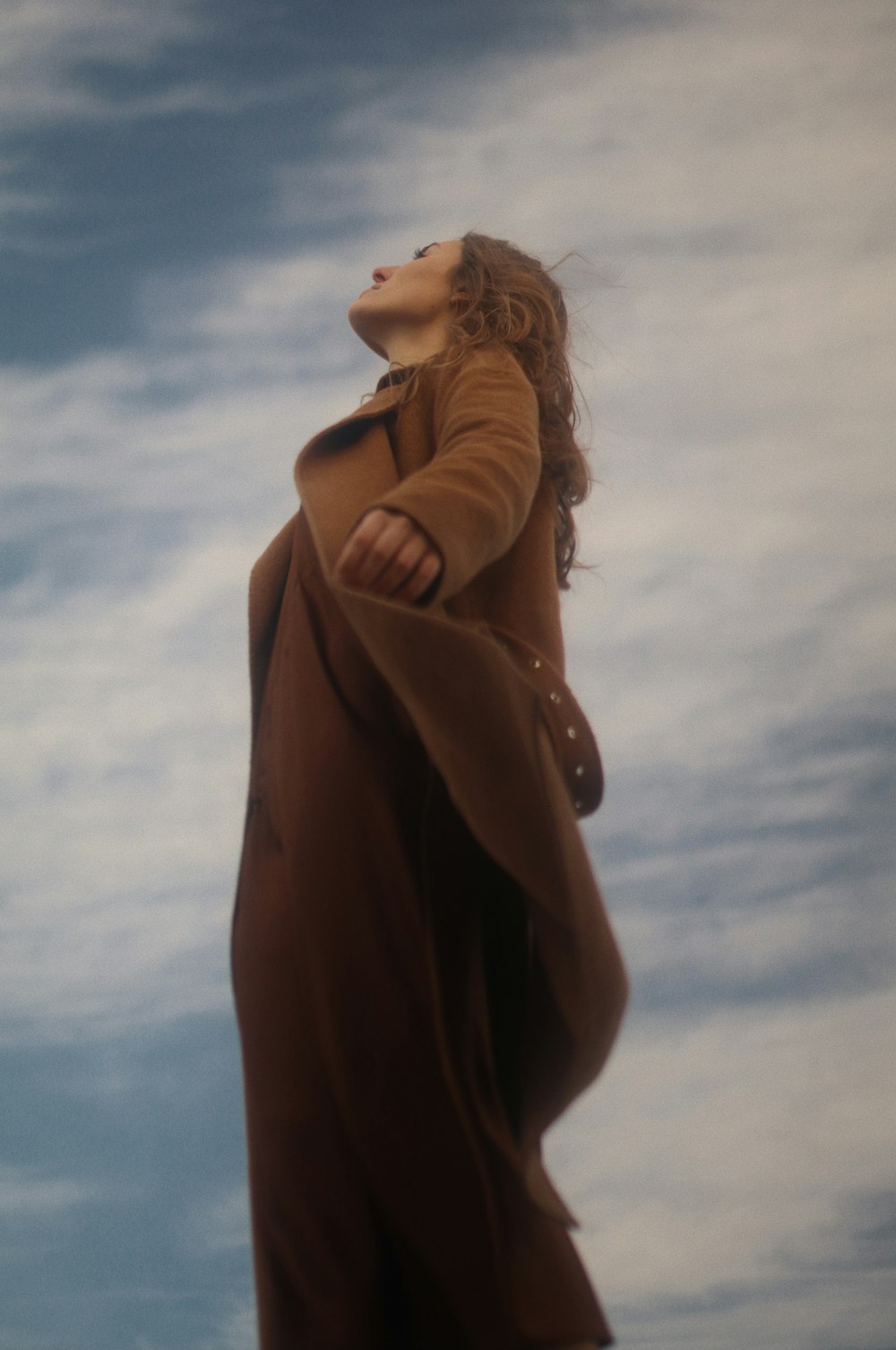 woman in brown long sleeve dress under white clouds and blue sky during daytime