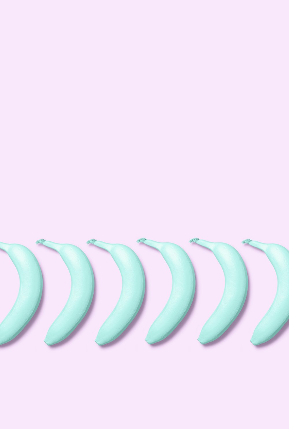 a row of blue bananas on a pink background