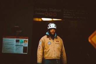 a man in a yellow jacket is standing in front of a subway station