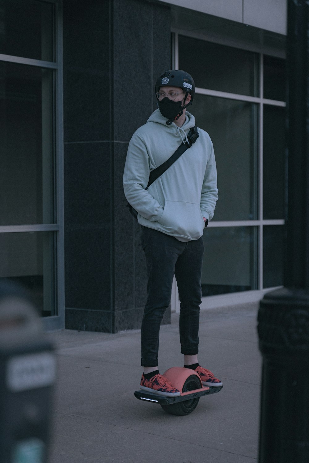 man in blue dress shirt and black pants wearing black sunglasses standing on gray concrete floor