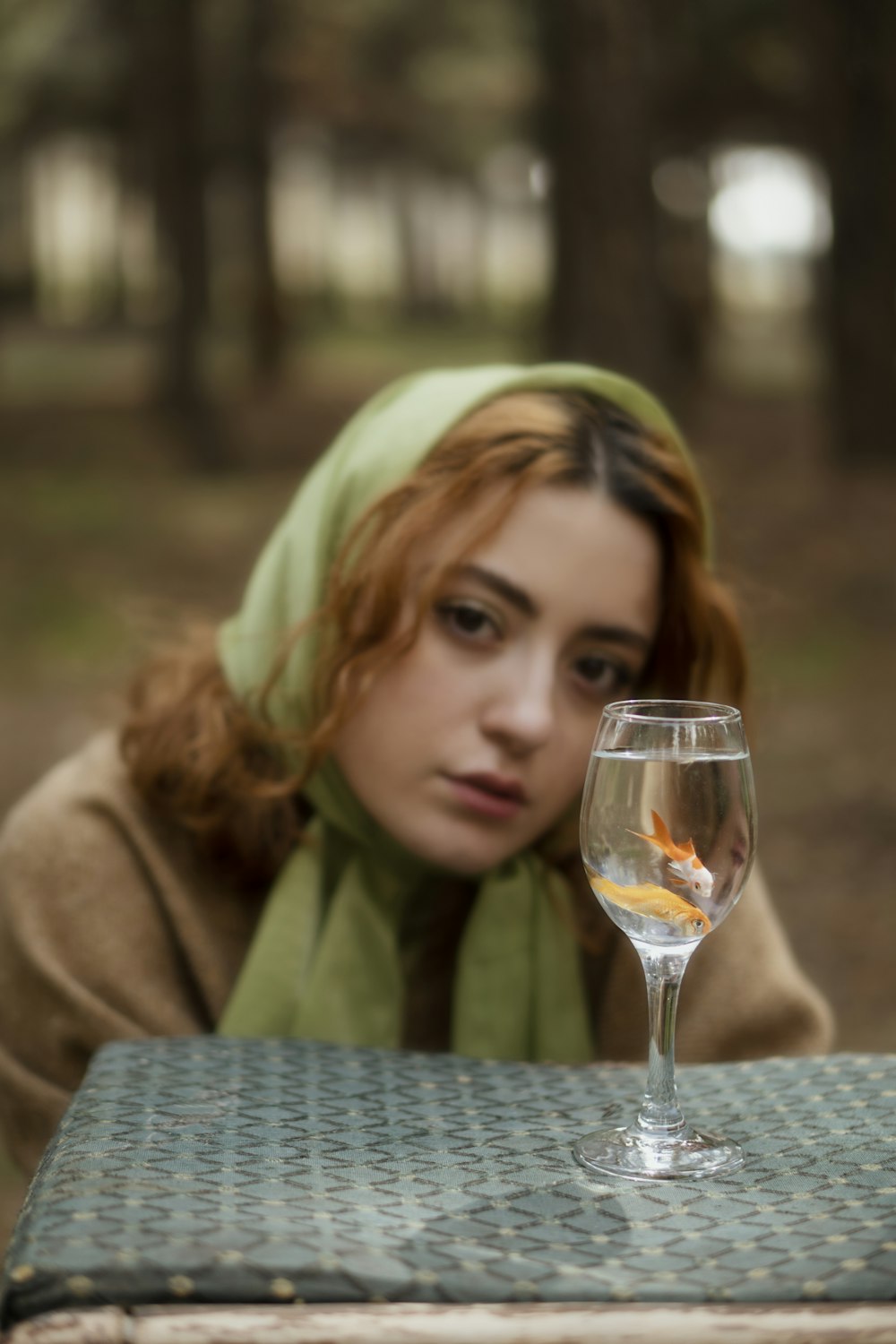 blonde woman in green scarf holding clear wine glass