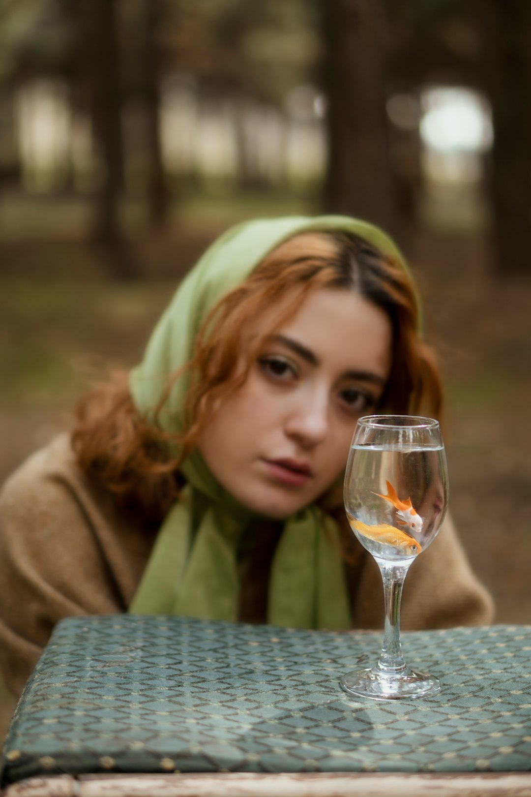 blonde woman in green scarf holding clear wine glass