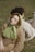 A woman with closed eyes lies on a man's back in a grassy outdoor setting. She is wearing a light green headscarf and a brown sweater, while the man is dressed in beige attire. The setting appears calm and serene, with soft lighting emphasizing a peaceful moment.