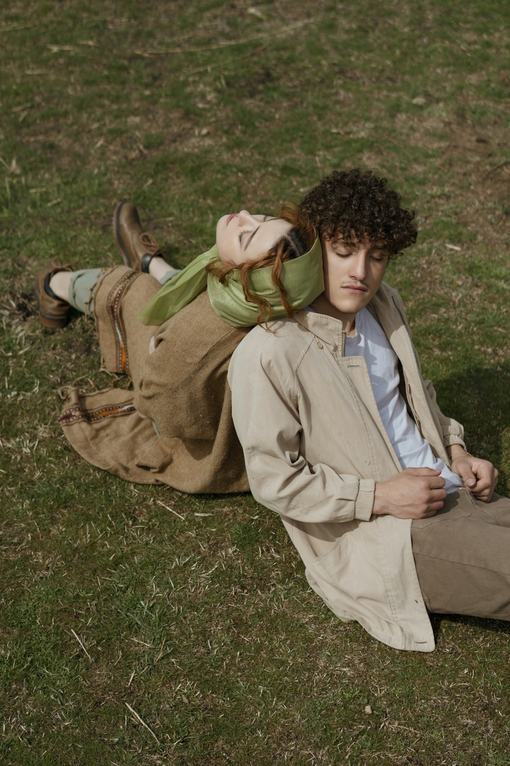 woman in brown coat sitting on green grass field during daytime