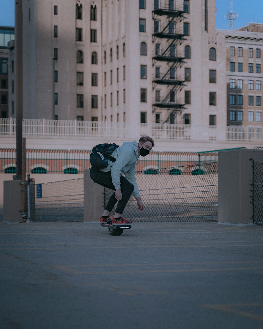homem em jaqueta cinza andando no skate preto durante o dia