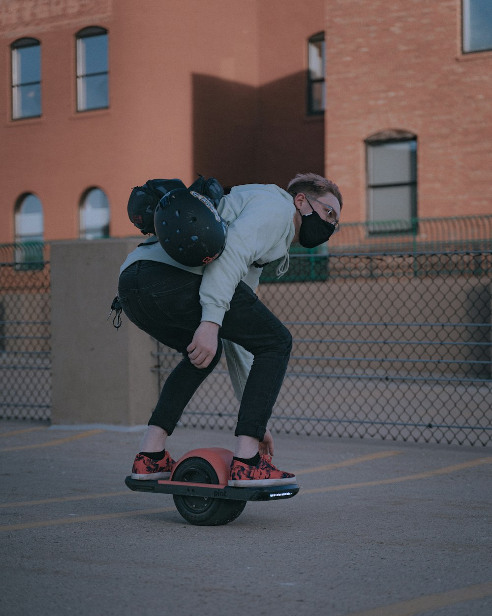 man in white shirt and black pants riding red skateboard during daytime