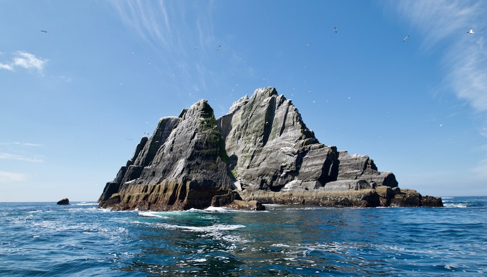 昼間の水域のそばの灰色の岩山