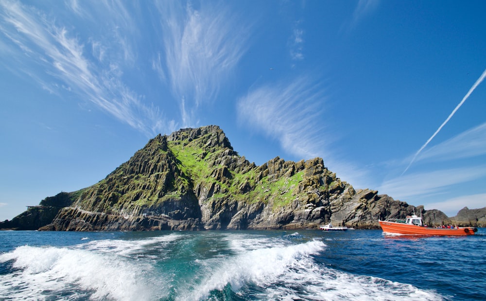 formazione rocciosa verde e marrone sul mare sotto il cielo blu durante il giorno