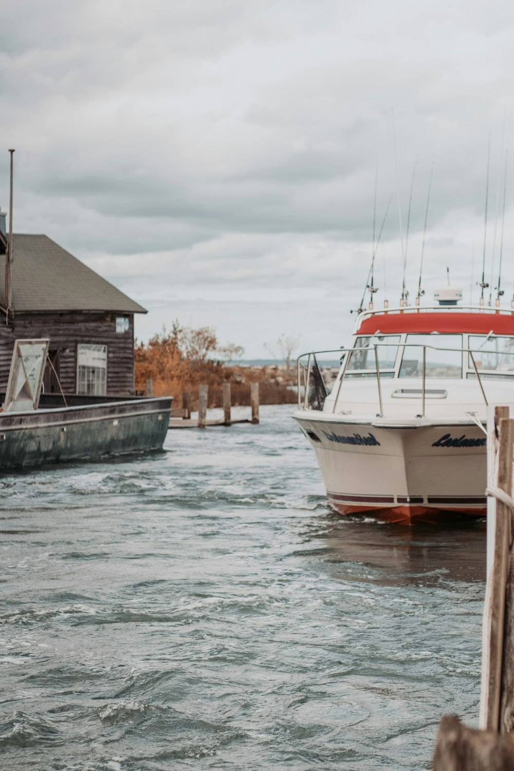 white and red boat on water near brown wooden house during daytime