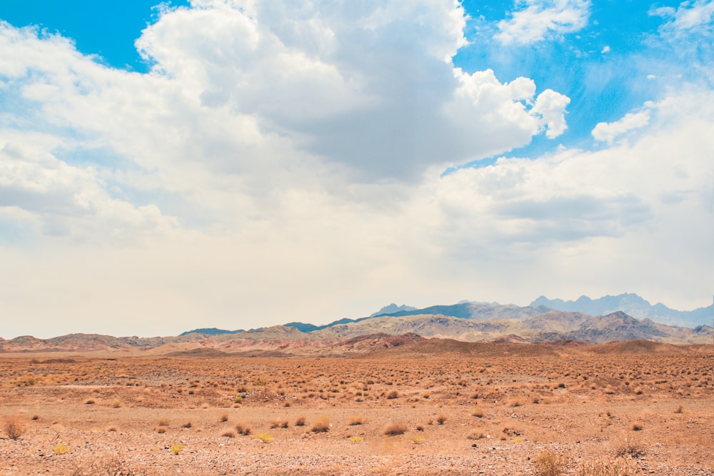 brown sand under white clouds and blue sky during daytime