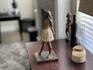An elegant bronze sculpture of a dancer frozen in mid-motion, displayed on a wooden pedestal.