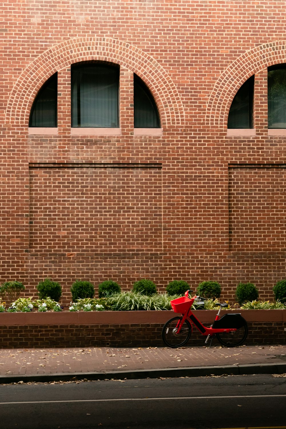 Rotes Fahrrad tagsüber neben braunem Betongebäude geparkt