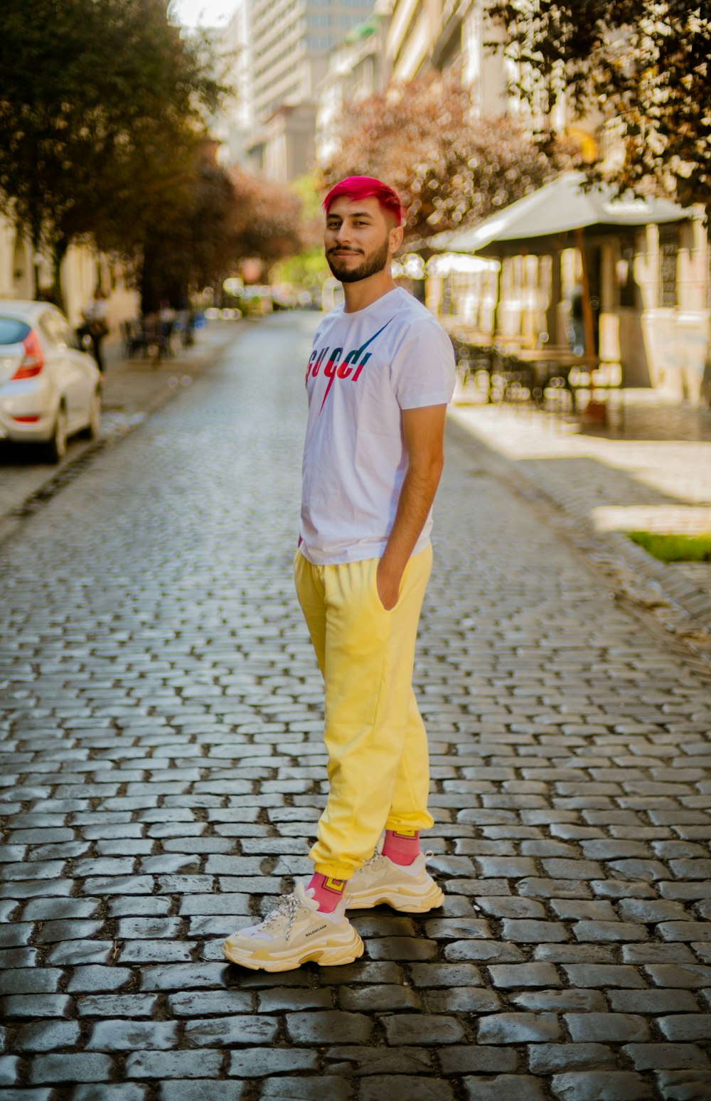 woman in white t-shirt and yellow pants standing on gray concrete pavement during daytime