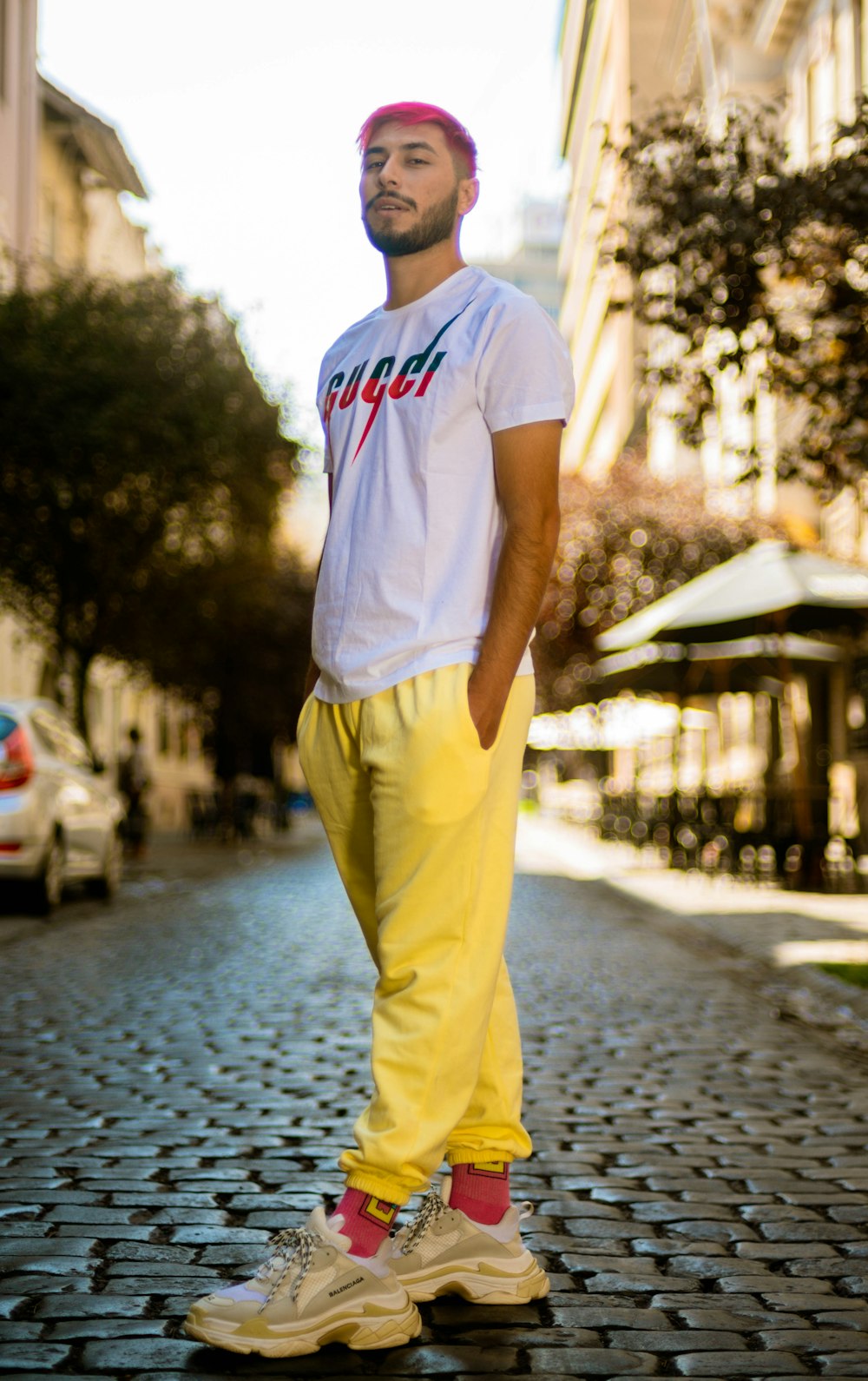 man in white crew neck t-shirt and yellow pants standing on road during daytime