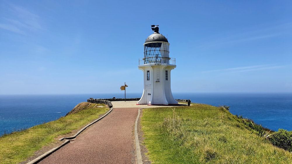 white lighthouse on green grass field under blue sky during daytime