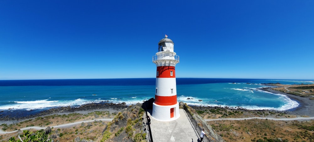 Faro bianco e rosso vicino al mare durante il giorno