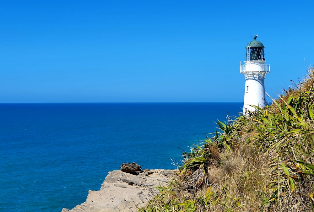 white lighthouse near blue sea under blue sky during daytime