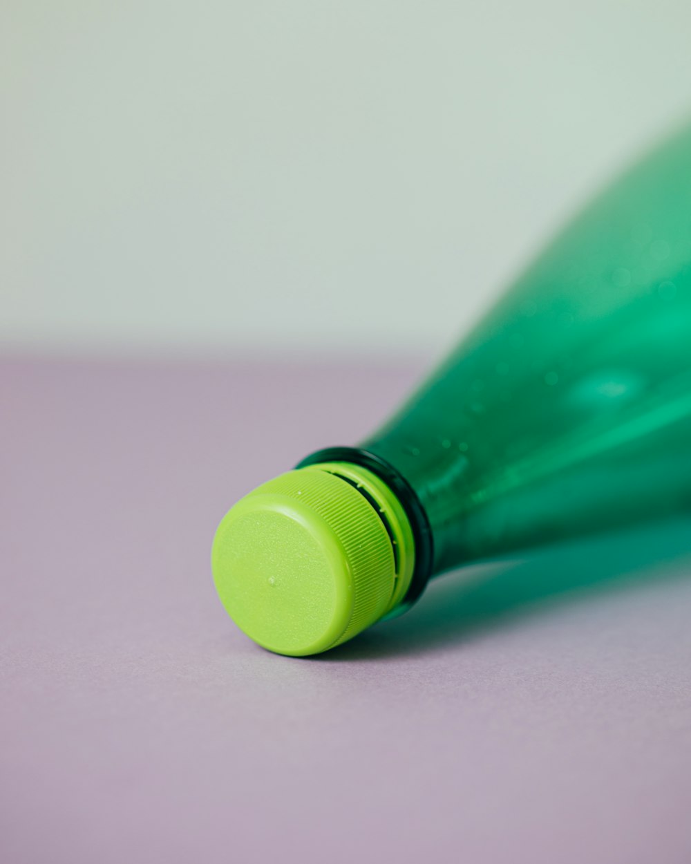 bottiglia di plastica verde su superficie rosa