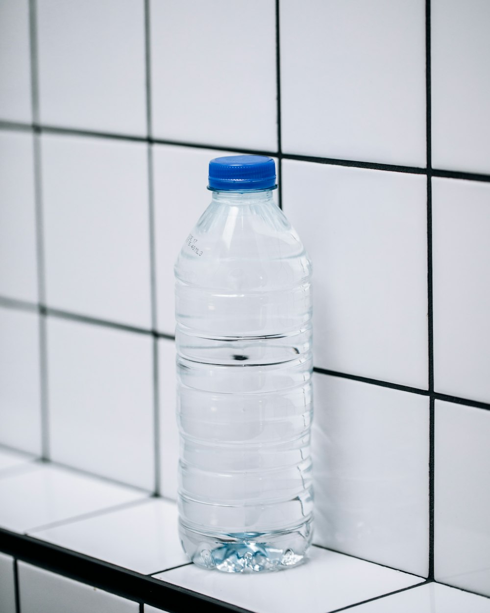 Botella de plástico transparente sobre baldosas de cerámica blanca