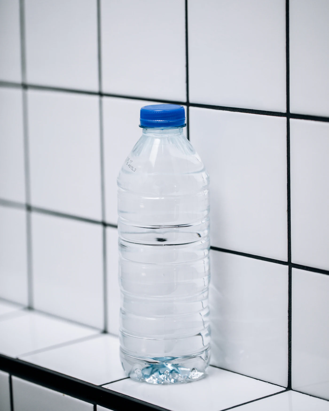 Clear plastic bottle photographed against a tiled surface