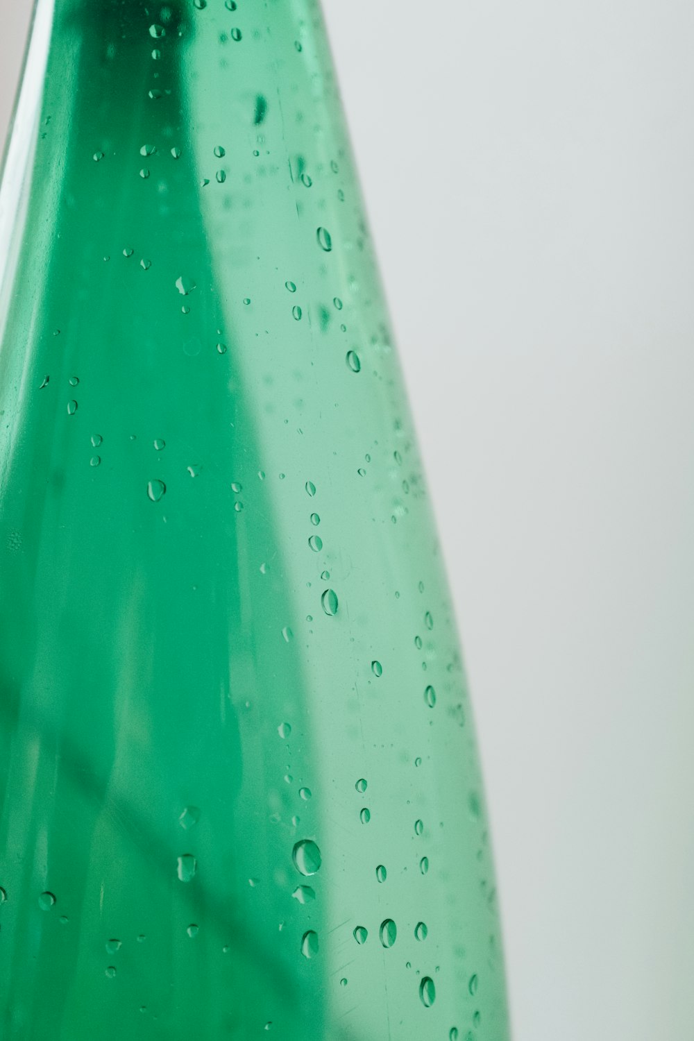 bottiglia di plastica verde con gocce d'acqua