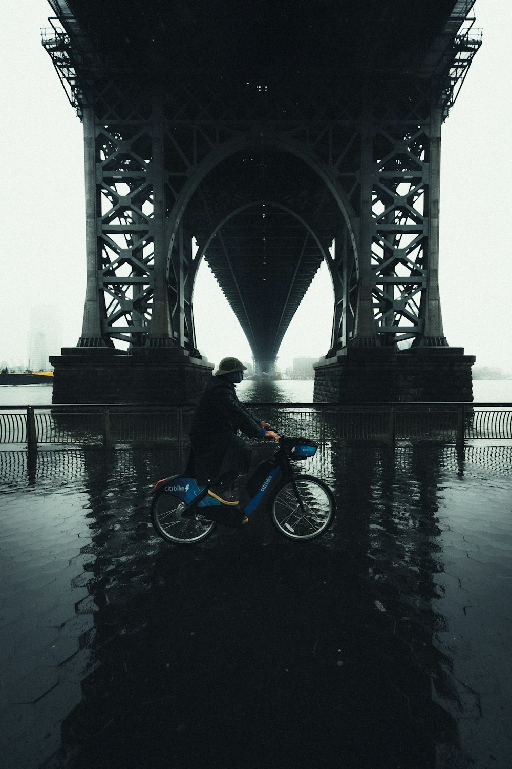 a person riding a bike under a bridge