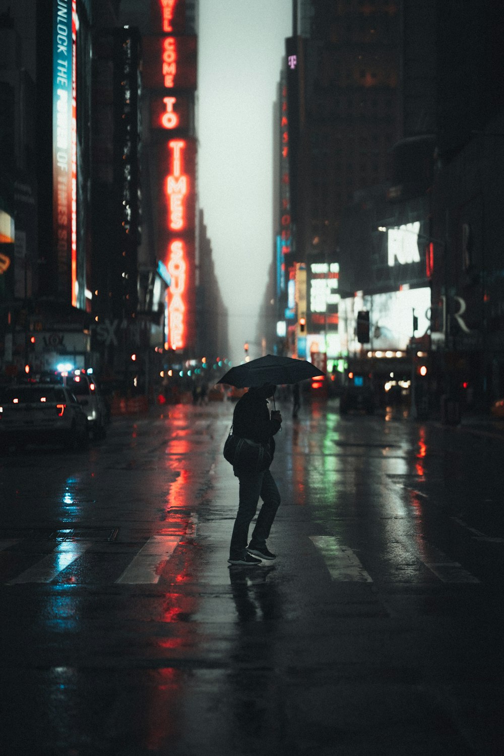 person in black jacket and black pants holding umbrella walking on street during daytime