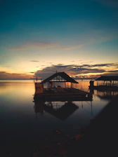 A sleek modern floating house on calm water at sunset, reflecting warm light.