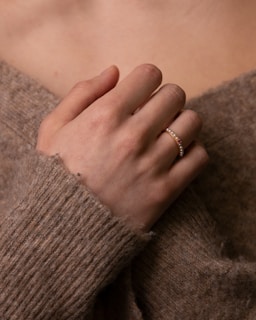 Hand holding a custom charm ring adorned with playful beads and a small flower accent.