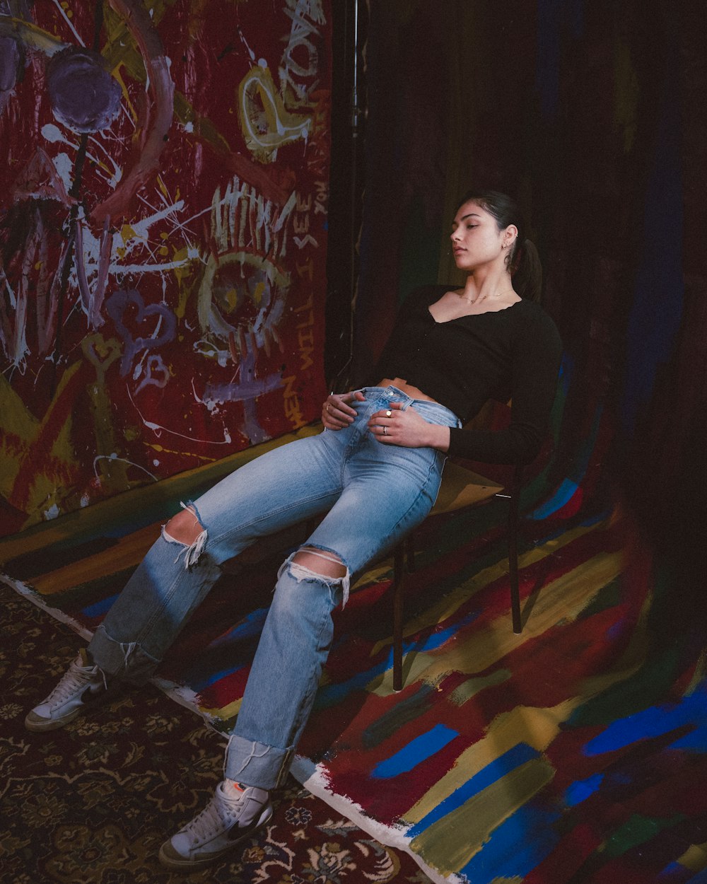 woman in black long sleeve shirt and blue denim jeans sitting on brown wooden bench