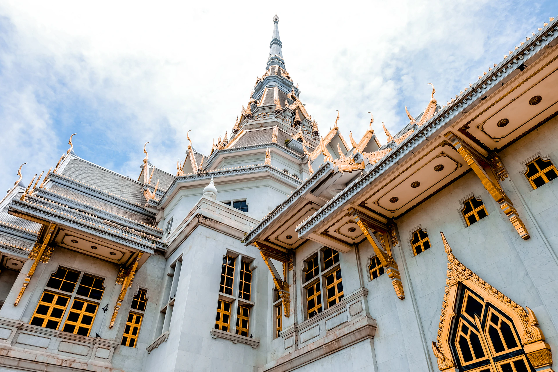 a serene view of the temple exterior at sunrise, with stone grey walls accented by saffron and light gold decorations under a clear sky