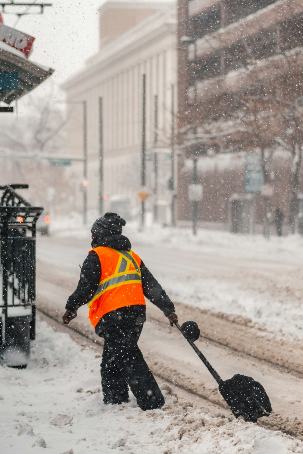 man in orange jacket and black pants walking on snow covered ground during daytime