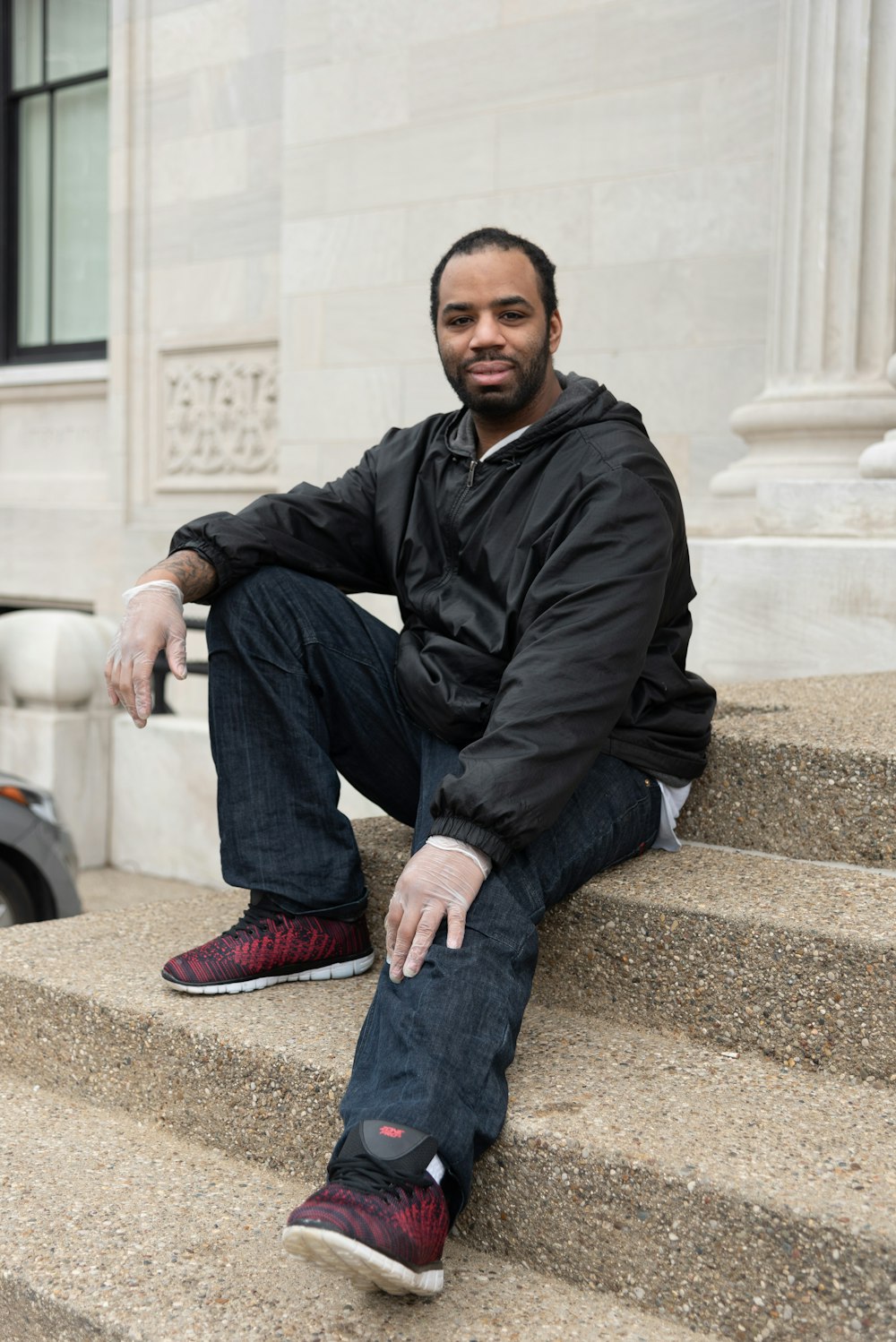 man in black leather jacket sitting on concrete bench