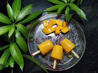 Fresh fruit ingredients like mangoes, berries, and kiwi arranged artistically beside popsicles.