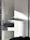 A white cabinet with multiple compartments, including a partially open drawer. Soft natural light creates shadows and highlights on the surface. A person is partially visible at the bottom right corner, possibly assembling or inspecting the cabinet.