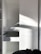 A white cabinet with multiple compartments, including a partially open drawer. Soft natural light creates shadows and highlights on the surface. A person is partially visible at the bottom right corner, possibly assembling or inspecting the cabinet.