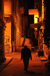 man in black coat walking on street during nighttime