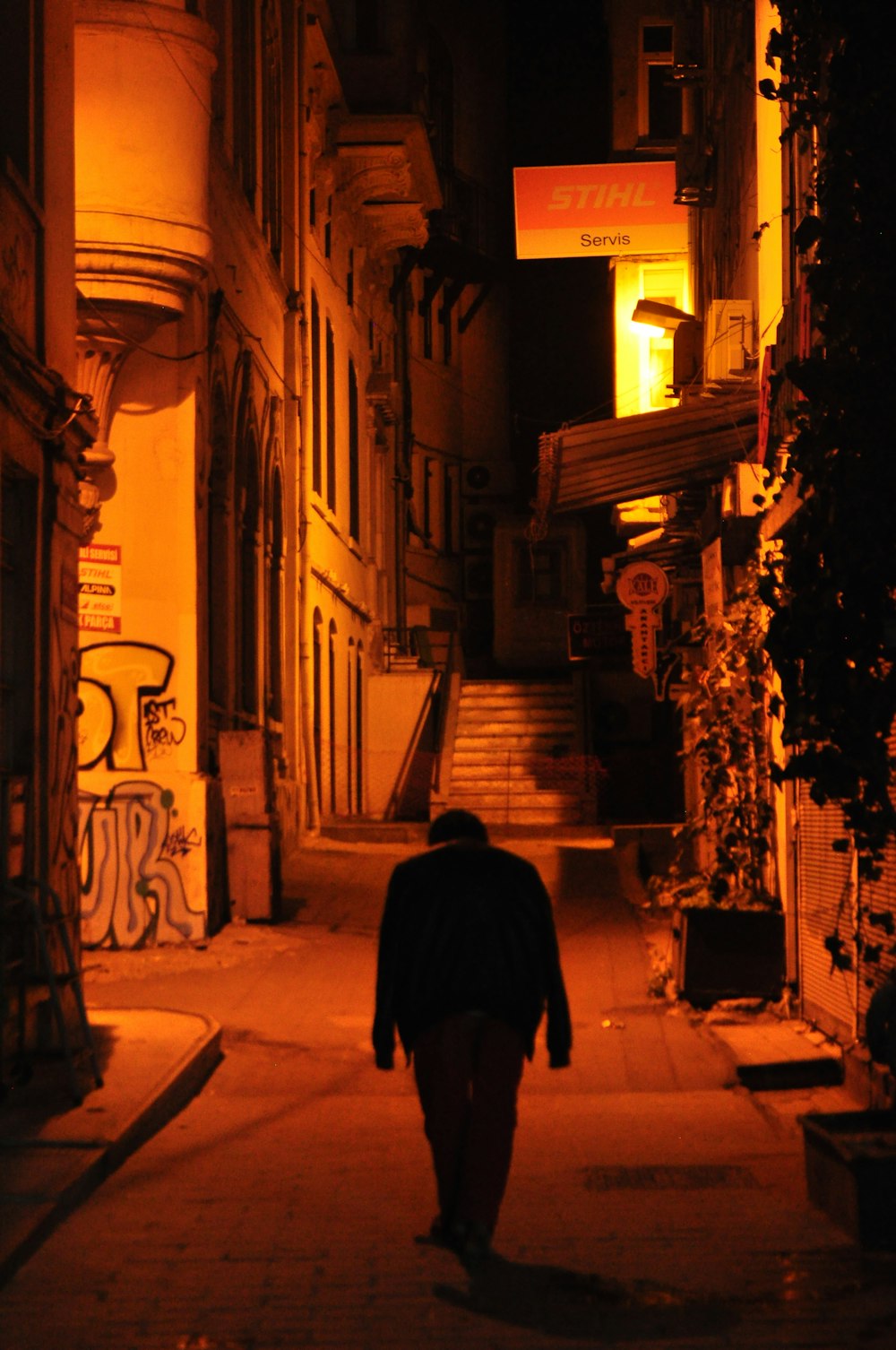 uomo in cappotto nero che cammina per strada durante la notte