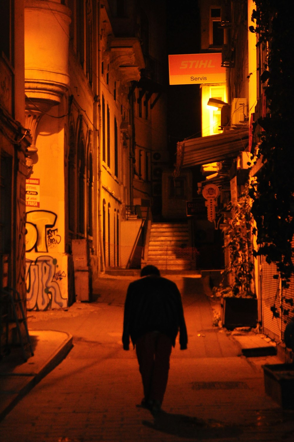 hombre con abrigo negro caminando por la calle durante la noche