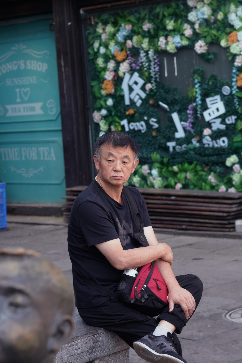 man in black polo shirt sitting on brown wooden bench during daytime