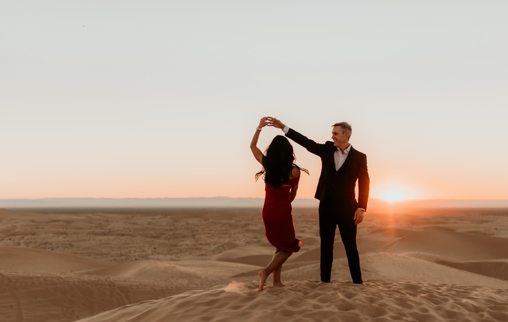 man and woman standing on brown sand during sunset