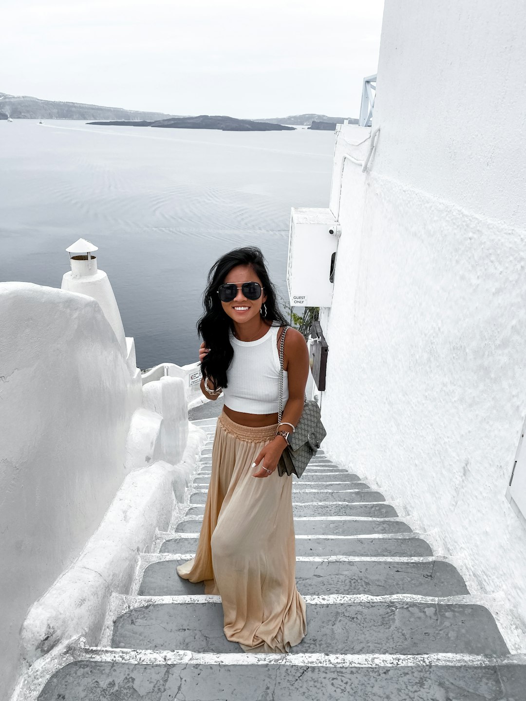 woman in white tank top and orange skirt standing on concrete stairs