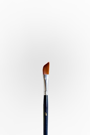 A sleek vylna ultra-precise brush resting on a reflective metallic surface.