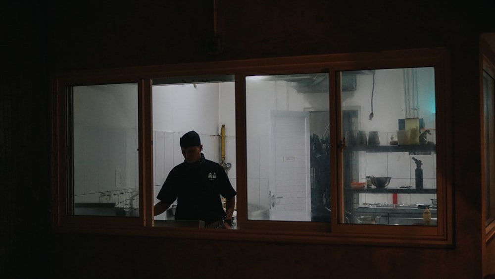 man in black shirt standing near window