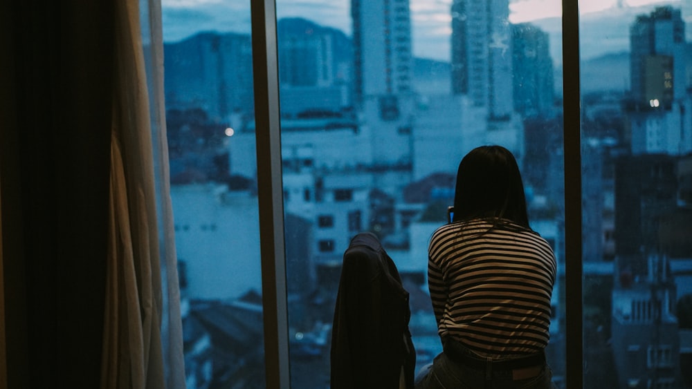 Frau in schwarz-weiß gestreiftem Langarmhemd steht in der Nähe des Glasfensters