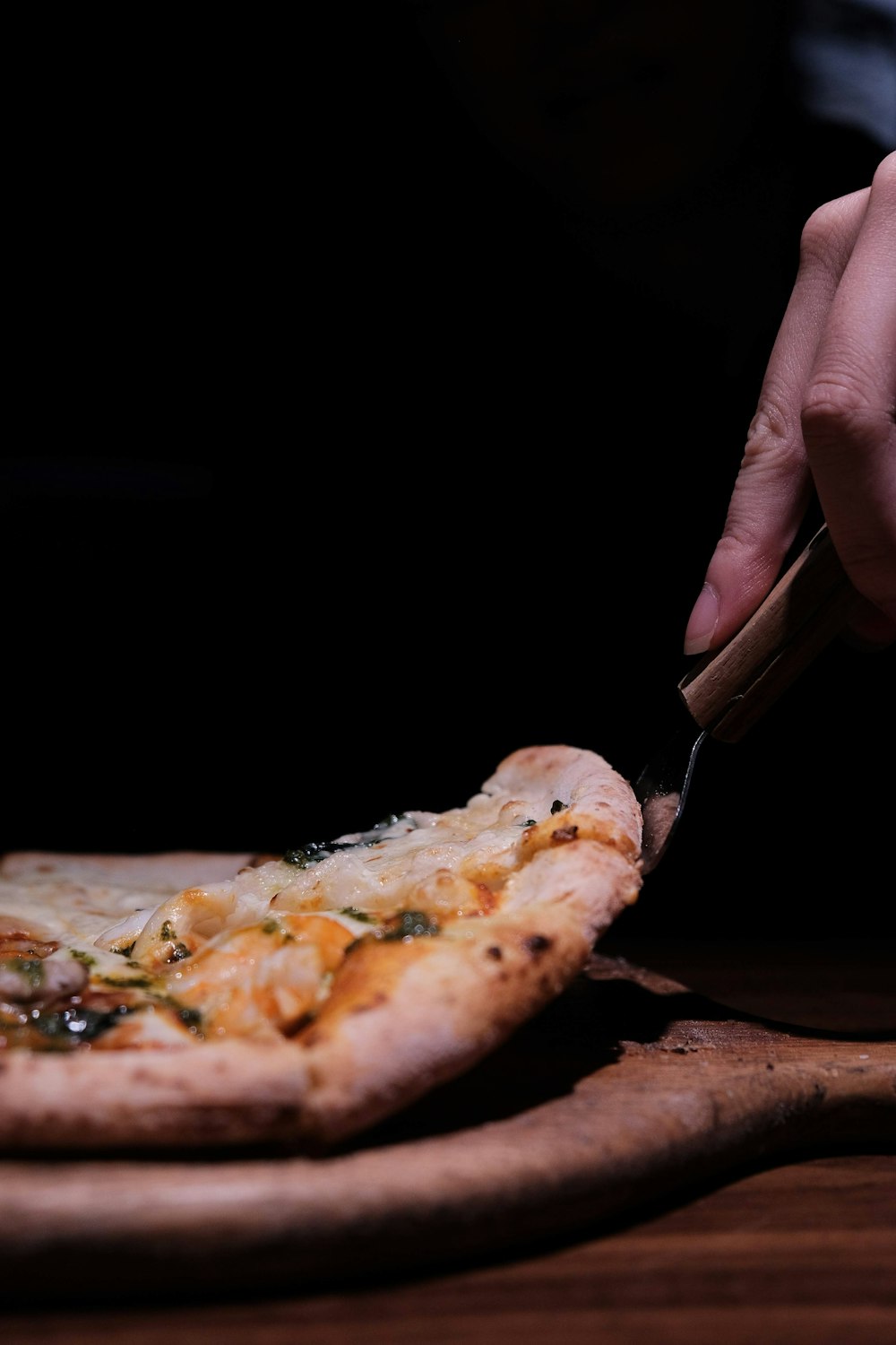 person holding sliced pizza with cheese